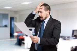 uomo disperato con mani in faccio e documento