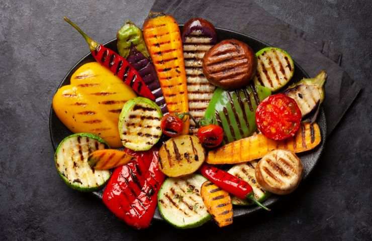 diverse verdure grigliate nel piatto su sfondo nero